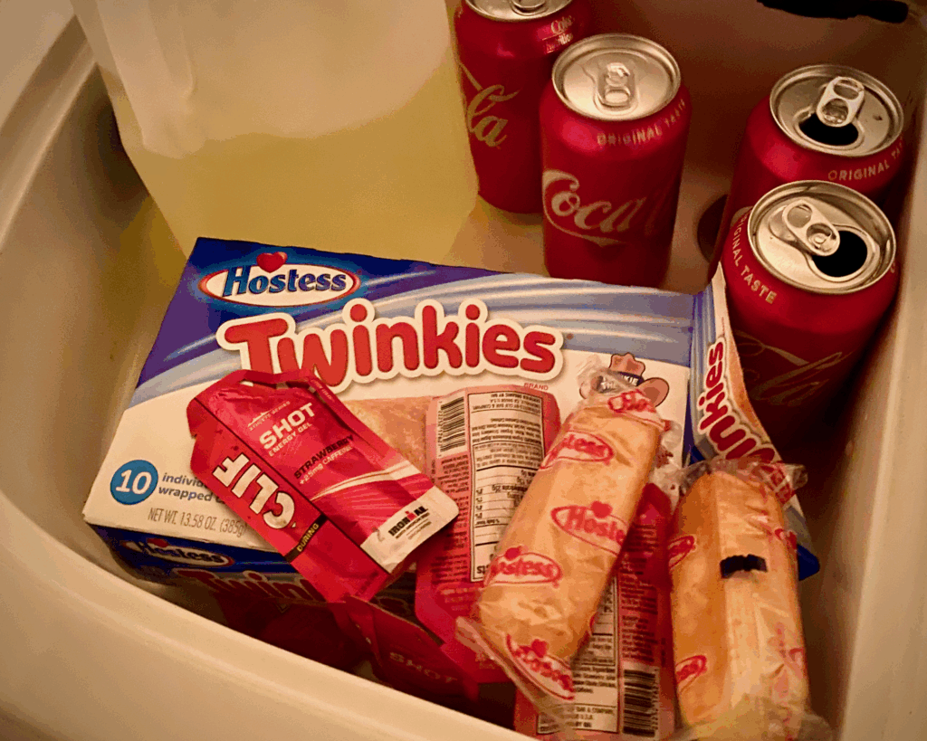 Twinkies, strawberry Clif Shots, and cans of Coca Cola arranged as marathon swim feeds